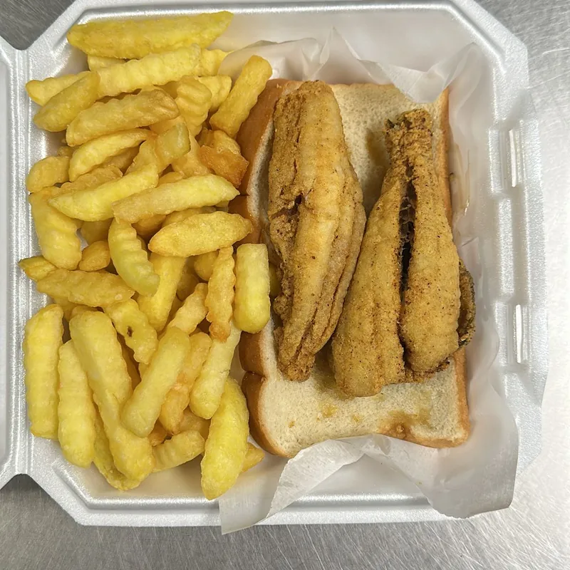 Fried fish sandwich on white bread with crinkle fries