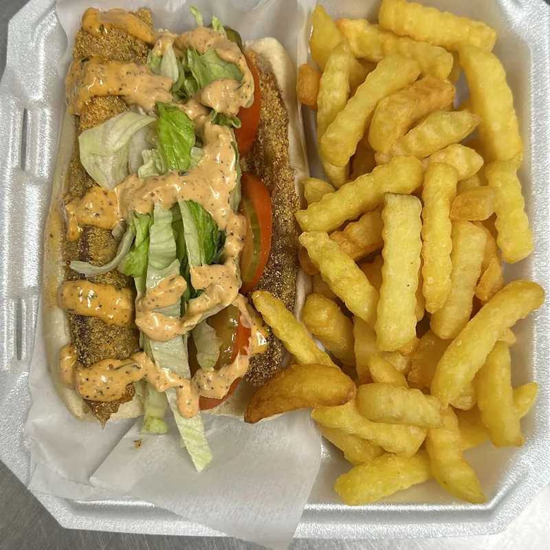 A dressed fish po-boy with lettuce, tomato and remoulade, with fries
